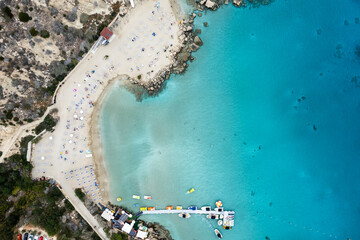 Drone view of idyllic sandy holiday beach. Konnos Bay beach people relaxing and enjoying summer holidays.