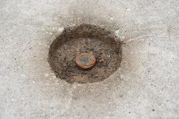 hole in a cement block with rusty metal button