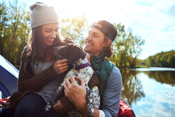 Adventure, couple and dog with love of camping in nature forest, sunshine and bond, smile and support of animal holiday. Happy, woman and man with puppy pet for care, hug or relax in summer journey