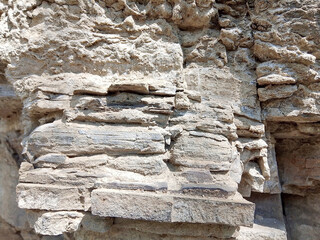 A close-up image of the weathered and textured surface of a natural stone material.