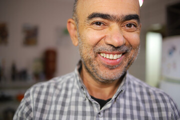 Homem de 50 anos, com barba branca , sorrindo, alegre em um ambiente interno em close.