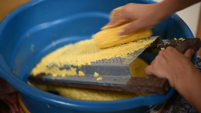 Grating yellow-green corn to make tamale.