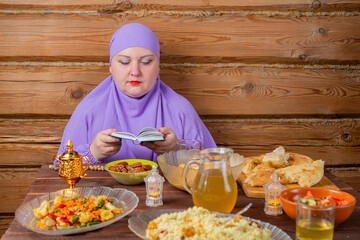 A Muslim woman in a lilac hijab at the table reads a dua from a book, a prayer for the end of...