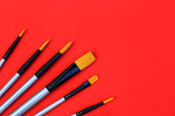a set of brushes for drawing on a red background. synthetic brushes for watercolor, gouache, acrylic