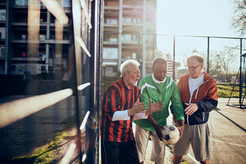 Senior friends playing soccer together in a park