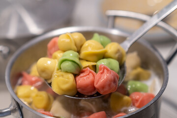 In a pot, colorful dumplings are being boiled. Preparing lunch or dinner