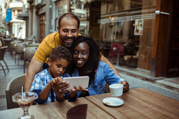 Happy multiracial family taking a selfie at an outdoor cafe