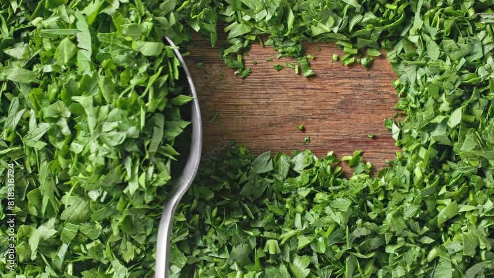 Poster chef spoons green fresh chopped parsley to prepare a healthy meal, top view. close-up of food