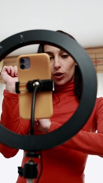 Content creator live-streaming with smartphone Ringling and tripod. Hispanic young woman recording
