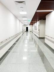 Empty modern hospital corridor, clinic hallway interior background with white chairs for patients waiting for doctor visit. Contemporary waiting room in medical office. Healthcare services concept