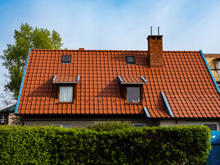 Obraz premium roof of a house made of red tiles with a chimney and attic