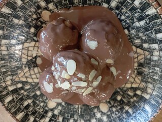 Delicious profiteroles with chocolate and white plate. Selective focus image on light background.