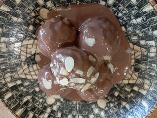 Delicious profiteroles with chocolate and white plate. Selective focus image on light background.