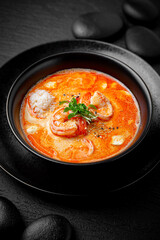 Composition of tom yam soup with shrimp and rice on black background. The Art of Japanese Cuisine. Food photography for menu and sushi bar decoration