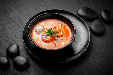 Composition of tom yam soup with shrimp and rice on black background. The Art of Japanese Cuisine. Food photography for menu and sushi bar decoration