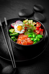 Salmon Poke bowl composition on black background. The Art of Japanese Cuisine. Food photography for menu and sushi bar decoration