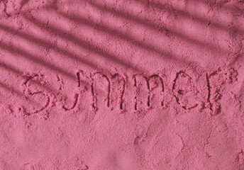 The word Summer handwritten on pink sand surface with tropical palm tree leaf shadow. Minimal...