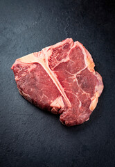Raw dry aged chianina porterhouse beef steak offered as close-up on rustic old board