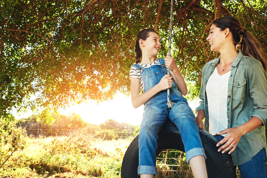 Smile, mother and girl on swing outdoor for bonding, laughing and play funny game together in nature. Happy, mom and push kid in playground on park tire for love, care and family connection in summer