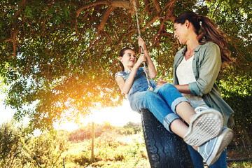 Smile, mother and child on tire swing outdoor for bonding and play fun game together in nature. Happy, mom and push girl in playground at park for love, care and family connection in summer sunshine