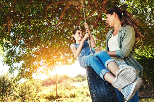 Smile, mother and child on tire swing outdoor for bonding and play fun game together in nature. Happy, mom and push girl in playground at park for love, care and family connection in summer sunshine