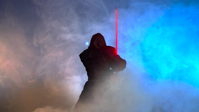 A space star warrior in a hooded cloak holds a lightsaber in his hands against the background of the starry sky render 3d