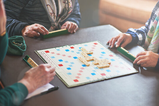 Board game, table and senior people playing in nursing home for retirement and friendly contest. Crossword, puzzle and battle of elderly woman in house winning with strategy, choice and challenge