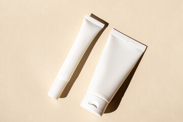 Skincare tubes with artistic shadow on neutral background