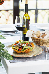 Fine dining in restaurant. Table served with tableware, salad, glass of wine and bread basket