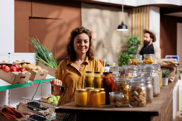 Portrait of smiling woman looking for fresh vegetables in eco friendly zero waste store. Happy...