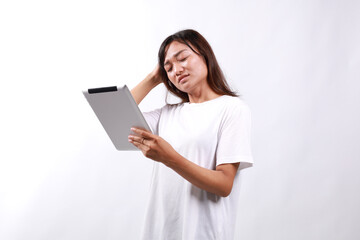 Attractive young asian woman holding a digital tablet while standing over white background with confused face expression