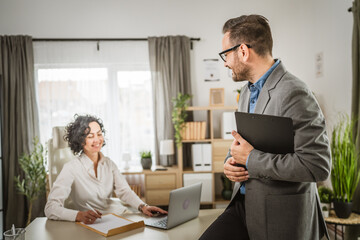 Obraz premium Adult man with clipboard look how woman sign document and touch laptop