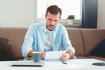 Focused man calculating budget at home