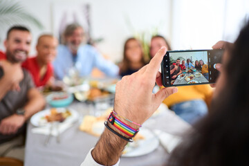 POV smart phone hold by caucasian man taking photo of reunion Caucasian family in celebration meal...