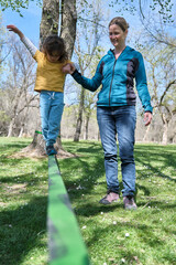 Mother supporting son doing slacklining in park