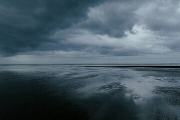 Storm clouds coming over a beach at sunset. Bethells Beach, Auckland, New Zealand.