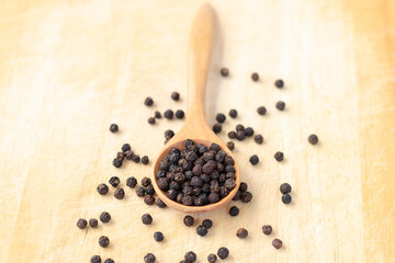 Peppercorns and black pepper in Wooden spoon placed on wooden floor.