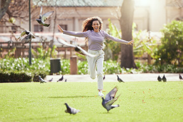 Woman, happy and chase pigeons in park on grass for comic games, adventure or excited in summer....