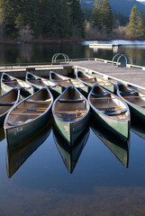 Canoes are reflected in the lake water during the summer on Alta Lake in Whistler BC