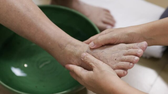 Female caregiver massage elderly woman foot before soak warm water.