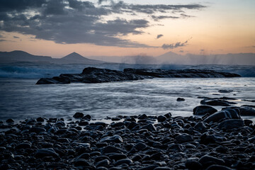 Serene and picturesque seascape during sunset..The foreground is adorned with smooth, dark stones...