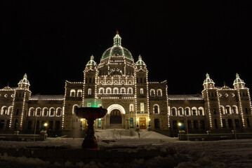The legislature of British Columbia on a snowy night in winter lit up by Christmas lights in Victoria BC