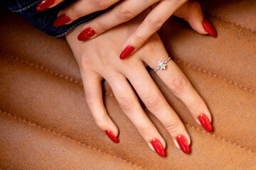 Beautiful female hand with red nails and diamond ring on finger