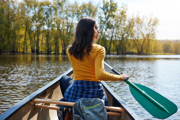 Woman, back and canoeing in nature on river, wellness hobby and backpack for supplies with paddle...