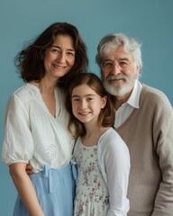 A warm family portrait featuring grandparents and their young granddaughter against blue background.