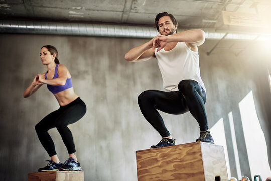 Jump, fitness and couple in exercise with box, power and training at workout challenge together. Man, woman and personal trainer at gym for balance, muscle development and healthy body at sports club