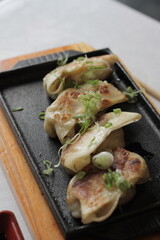 Golden-browned gyoza, delicate parcels filled with succulent meat or vegetables, offering a satisfying crunch on the outside and a burst of umami with every bite.