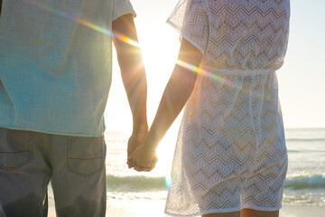 Obraz premium At beach, biracial couple holding hands, enjoying sunset