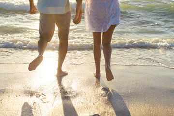 Obraz premium At beach, biracial couple holding hands, walking