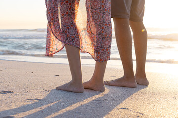 Obraz premium At beach, biracial couple standing, enjoying sunset